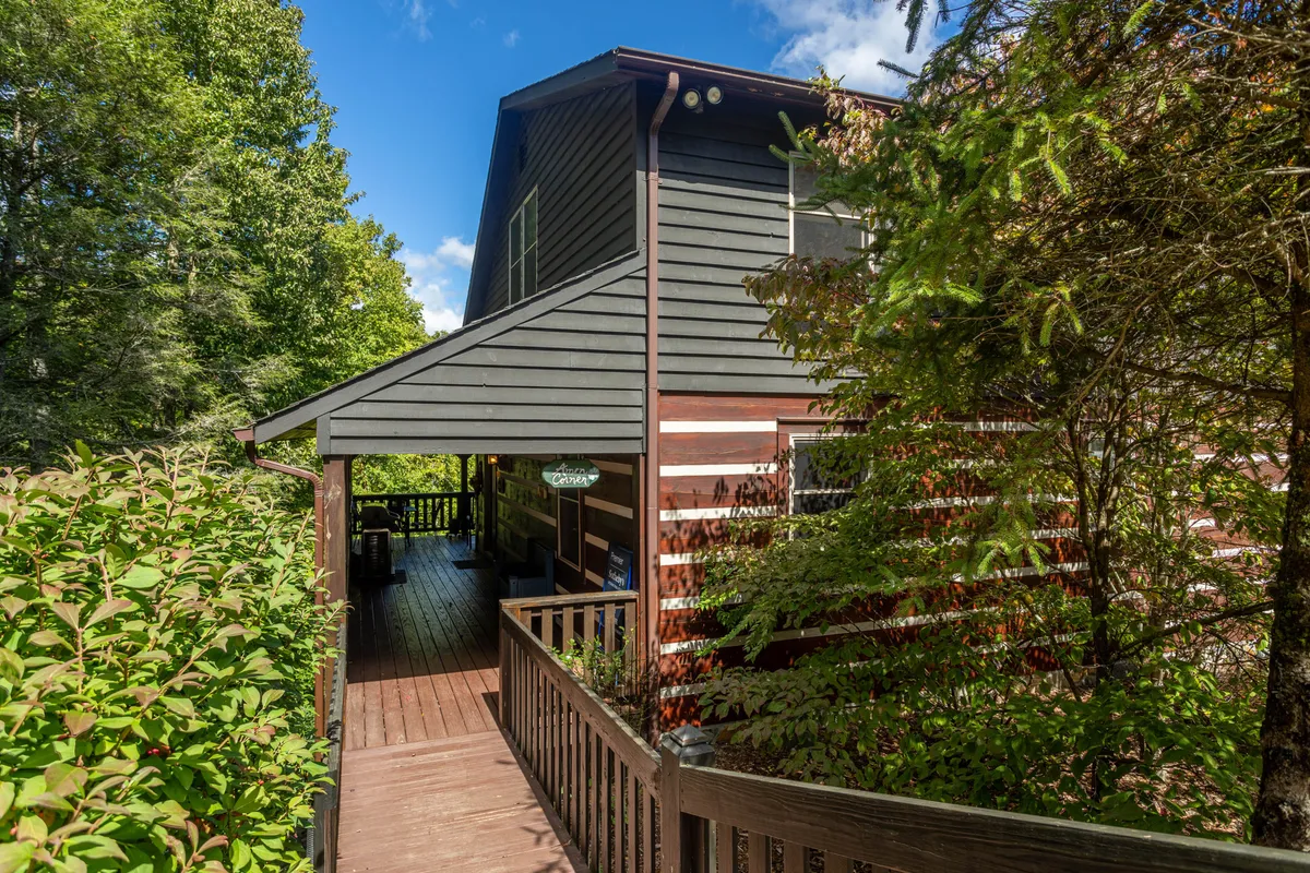 This image captures the exterior of Amen Corner's cabin, with a spacious wooden deck surrounded by lush greenery. The welcoming porch invites families to relax, gather, and watch sunsets after a day of exploring the nearby mountains. The natural setting highlights the convenience of stepping right into nature for hikes and creekside picnics.