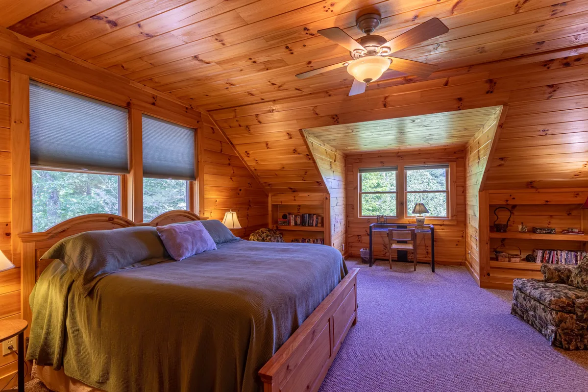 This image shows a tranquil bedroom with a cozy bed, windows letting in natural light, a reading nook, and a desk. The space feels private and restful, with soft bedding and a serene view of the outdoors, embodying a retreat-like ambiance suitable for couples or individuals.